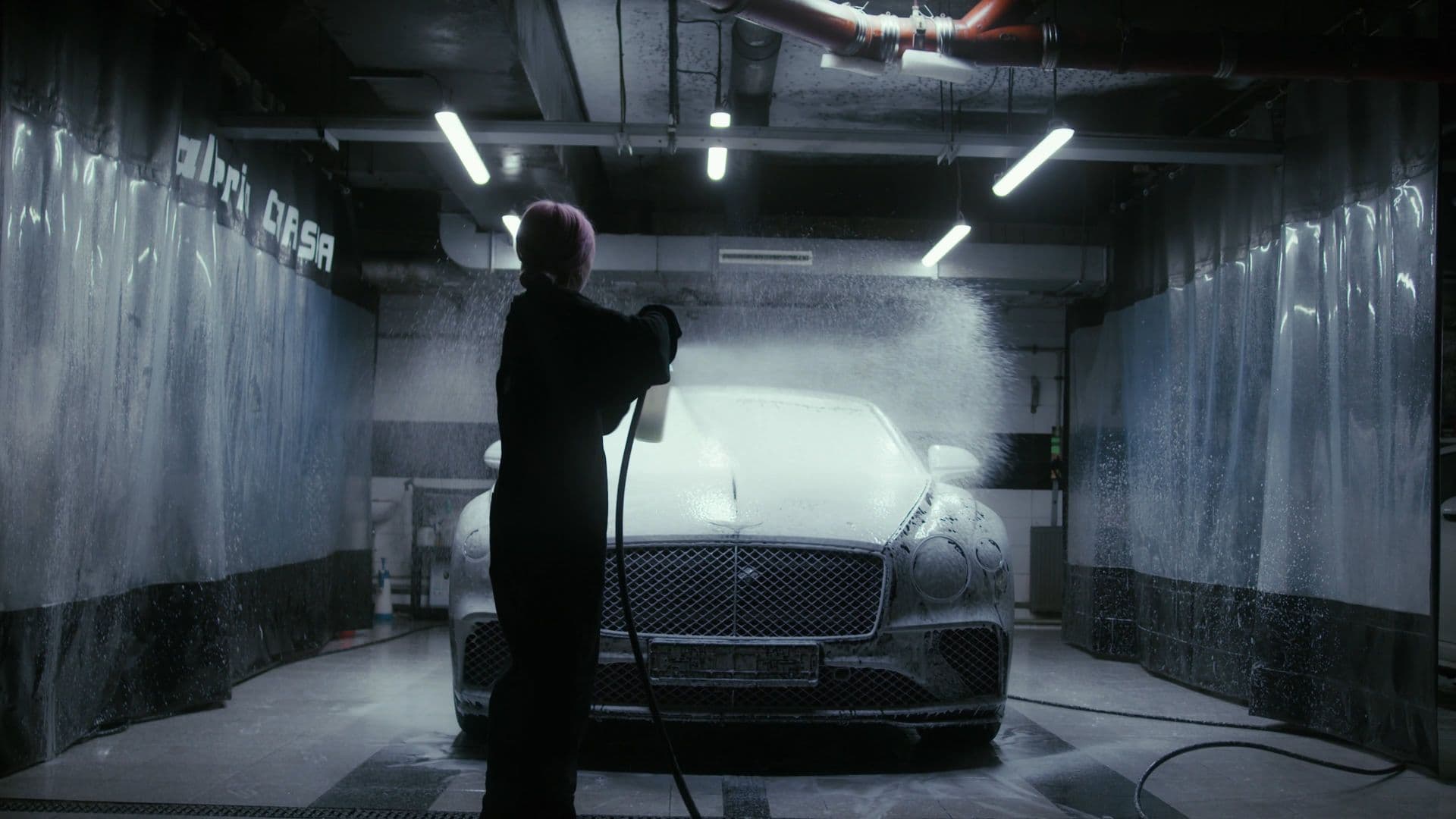 Detailer foaming a black Bentley in a professional wash bay
