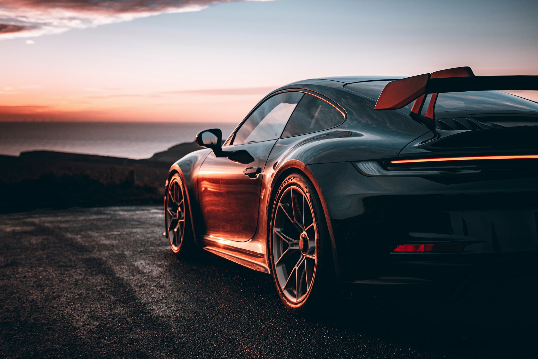 Dark Porsche 911 GT3 at dusk, its bodywork catching the last light